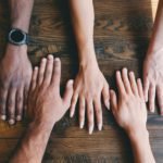 five human hands on brown surface