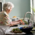 woman in purple and white floral shirt sitting on white bed