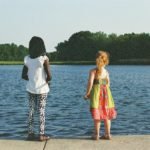 a couple of people that are standing in front of a body of water